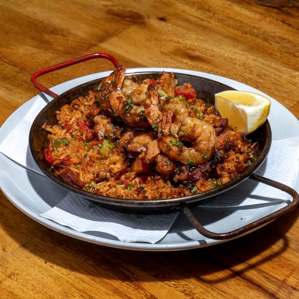 Creole jambalaya with shrimp, chicken, and vegetables in a skillet with a lemon wedge.