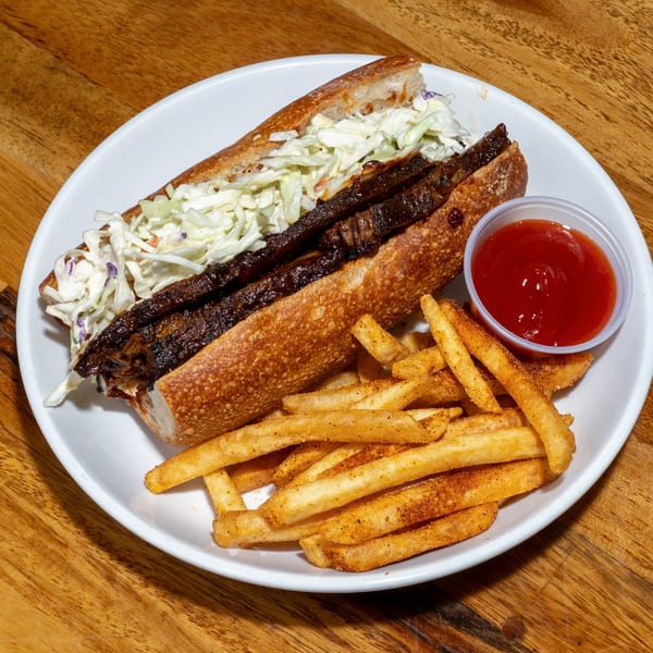 S/T Hooligans' Creole BBQ Brisket Po'Boy with coleslaw, served with seasoned fries and ketchup.