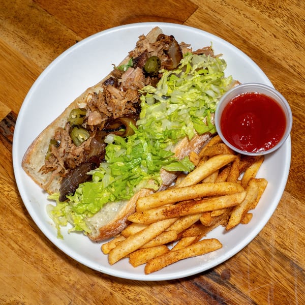S/T Hooligans' Creole pulled pork po'boy with lettuce, peppers, and a side of fries and ketchup.